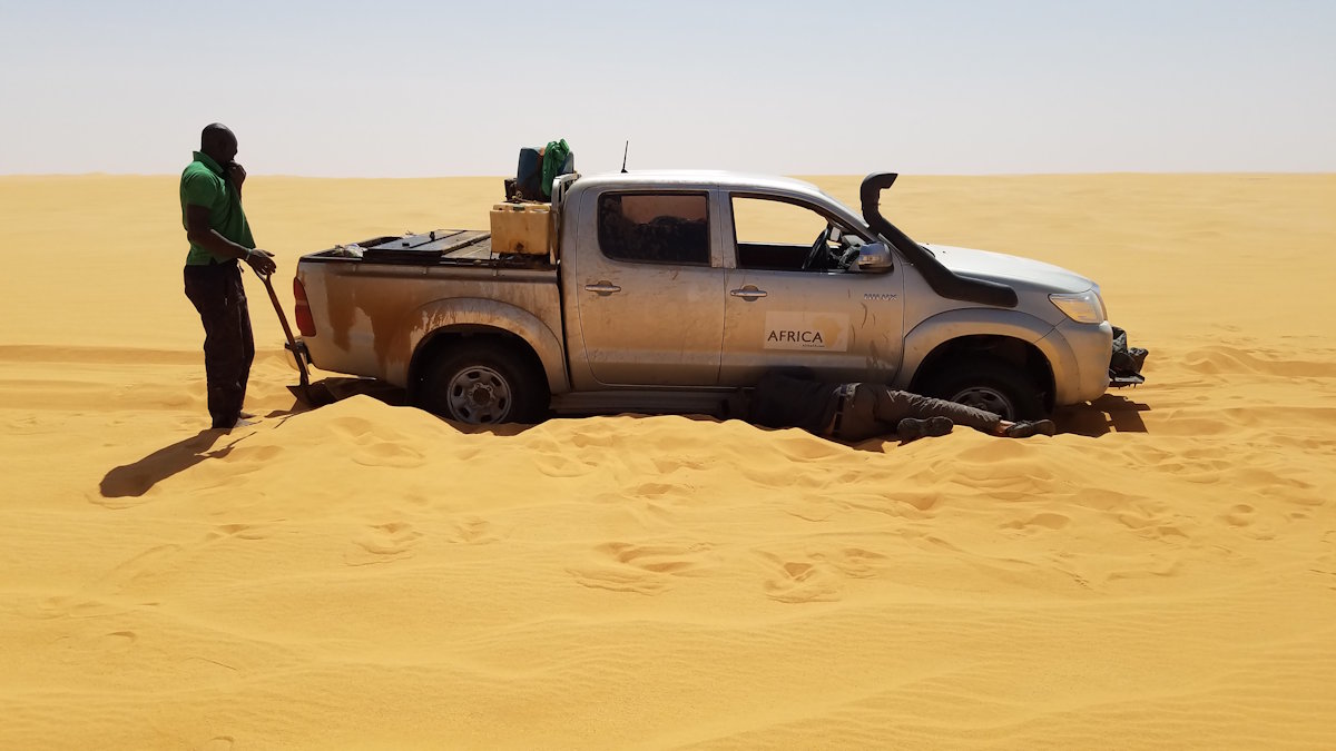 Egy homokba ragadt Toyota terepjáró a Szahara közepén a Csád–Líbia határ közelében, amit egy kameruni férfi próbálja kiszabadítani (Fotó: Wiki Loves Africa 2017/Francis Tapon/Wikipedia)
